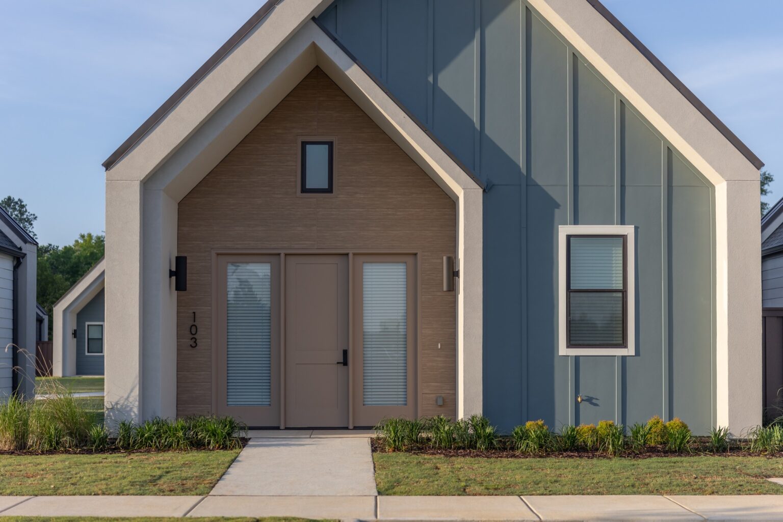 Fațadă modernă cu panouri fibrociment Nichiha, mix de textură lemn și panouri verticale gri-albăstrui, inspirație pentru proiecte din România.