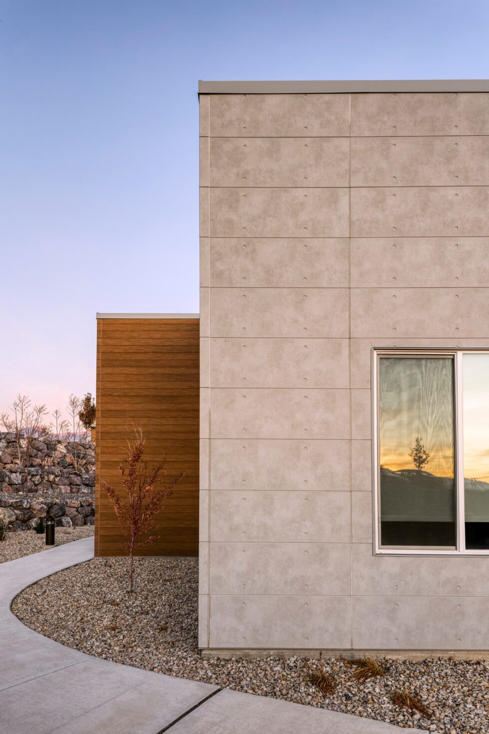 Casă modernă cu fațadă din panouri fibrociment Nichiha aspect beton și placare complementară aspect lemn, inspirație pentru România.